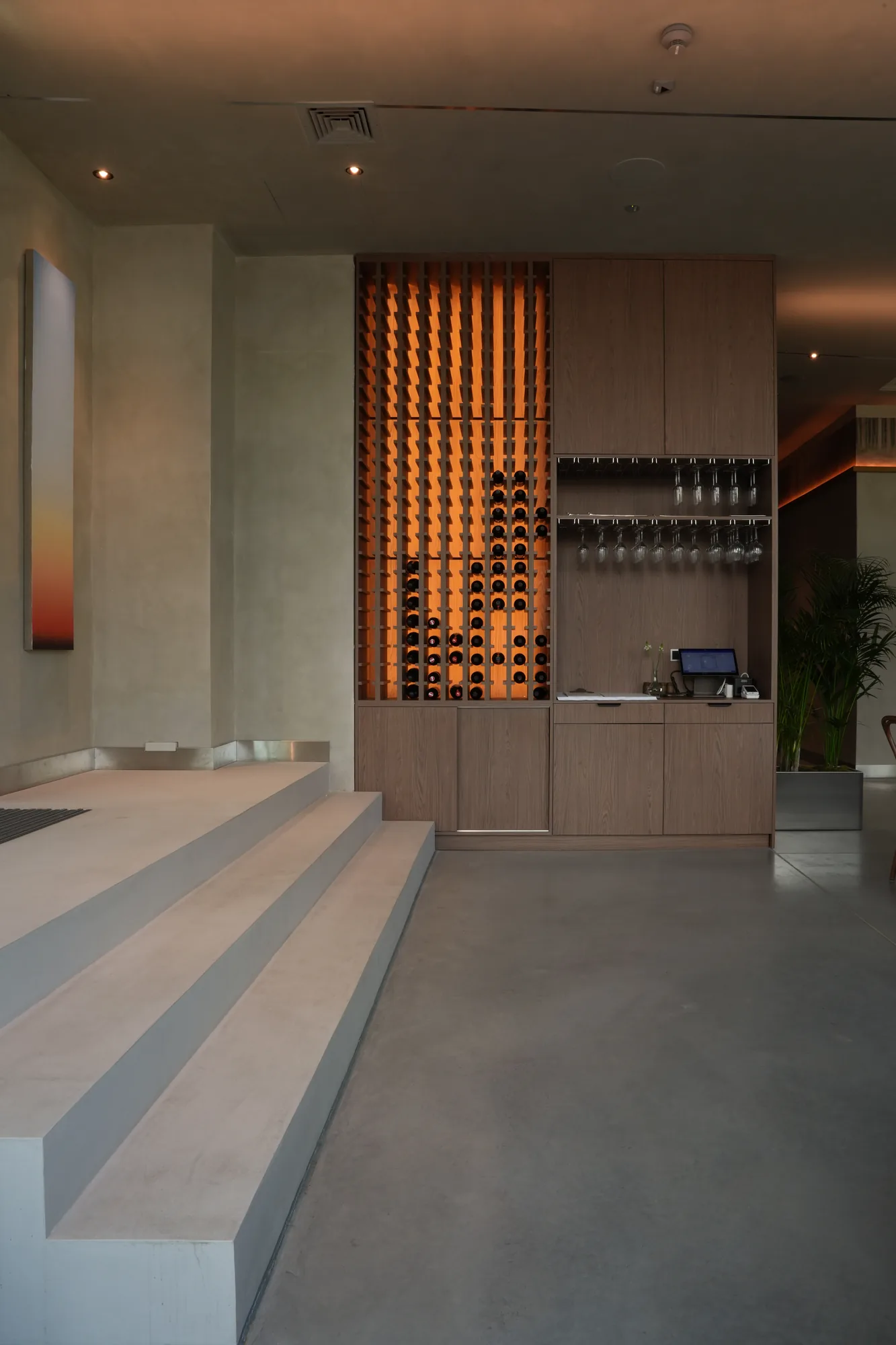 Podświetlana szafa na wina i betonowe schody w projekcie wnętrza restauracji Babajaga