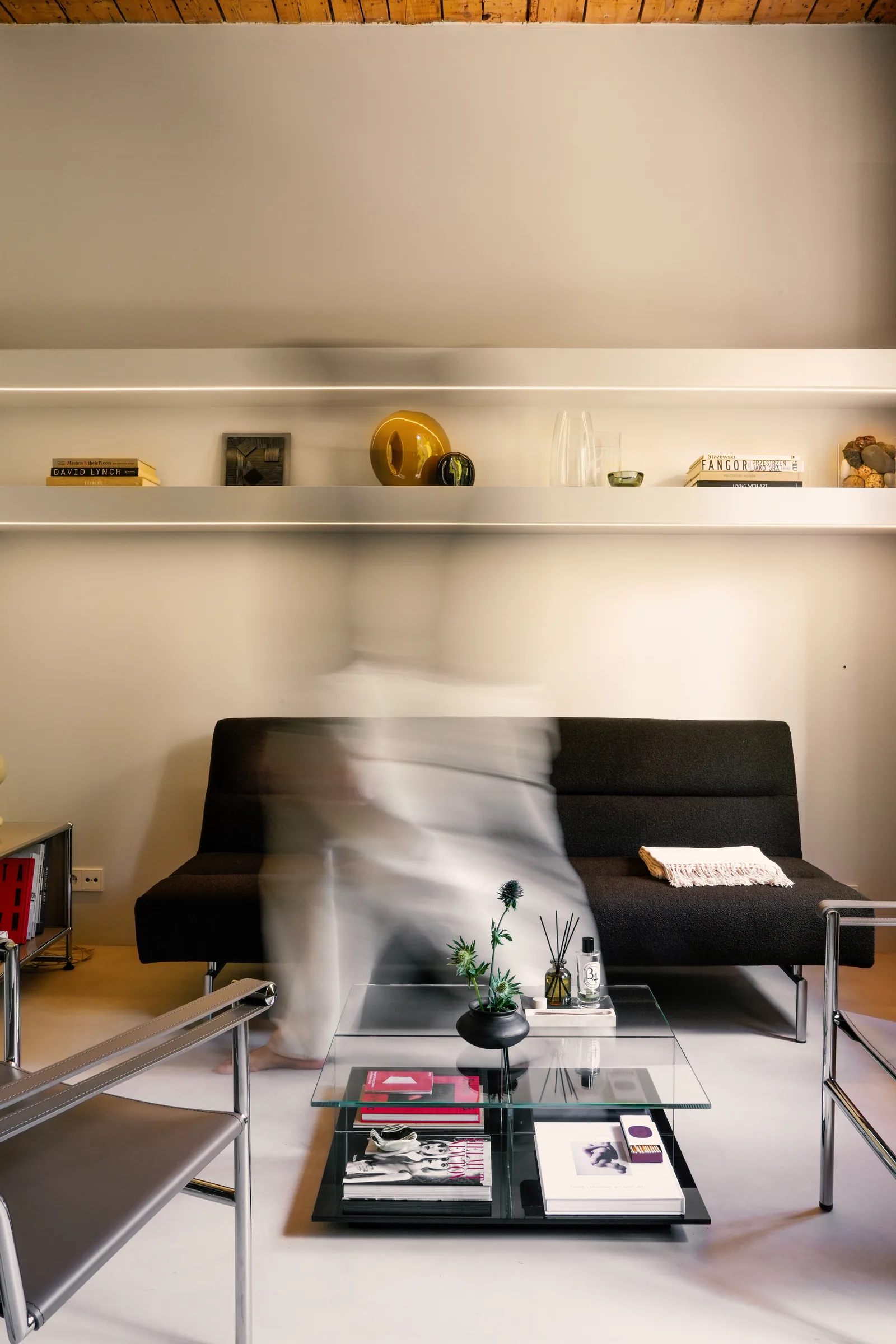 Strefa dzienna kawalerki — czarna sofa i podświetlane półki